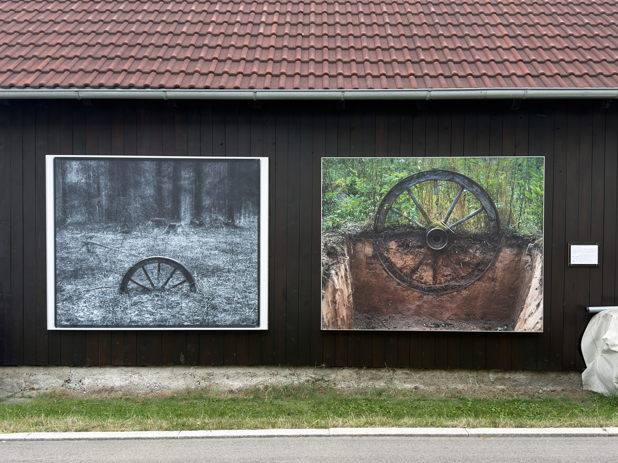 Blick auf die beiden ausgestellten Bilder an der Holzwand einer Scheune.
